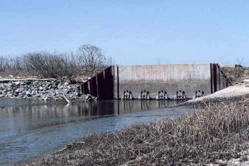 Figure 6.5 The tide gate at the mouth of Army Creek on the Delaware side of the Delaware River. The tide gate drains flood and rain water out of the creek to prevent flooding. The five circular mechanisms on the gate open and close to control water flow [Photo source: courtesy NOAA Photo Library].